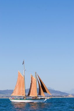 White Yacht, orange sail - copy space clipart