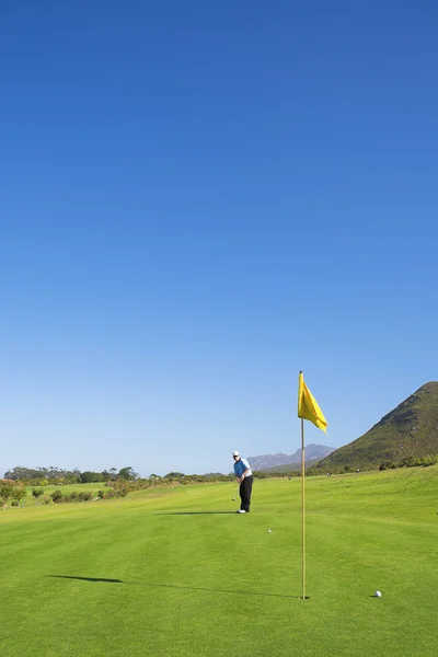 Een golfer golfen op een groen. — Stockfoto