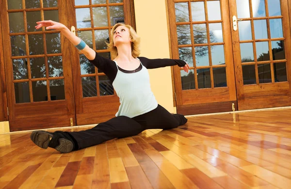 A Female Dancer practicing in her studio - in a split, on the floor — Stock Photo, Image