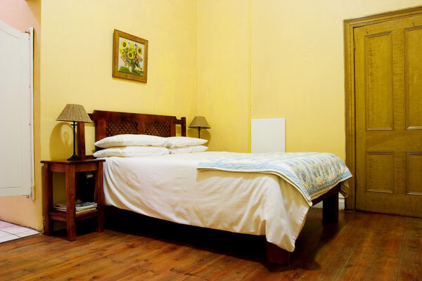 Интерьер комнаты с прикроватными лампами, деревянной кроватью и белым пододеяльником
