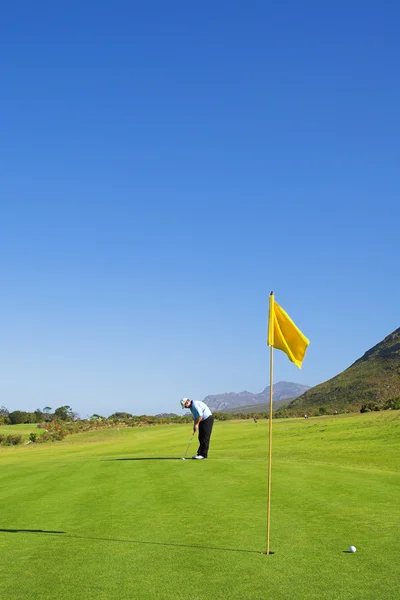 Um golfista jogando golfe em um verde . — Fotografia de Stock