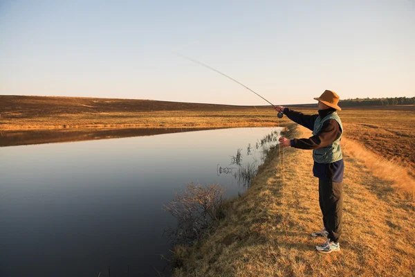 Un pescador de mosca lanzando una línea en Dullstroom, Sudáfrica — Foto de Stock