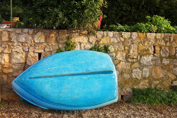 Old blue rowboat against a wall — Stok fotoğraf