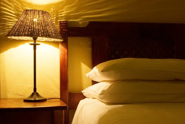 Interiér pokoje s lampičky, dřevěná postel a bílou peřinu — Stock fotografie