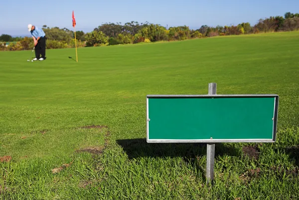 Een golfer golfen op een groen. — Stockfoto