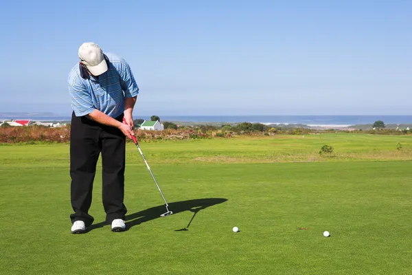 Een golfer golfen op een groen — Stockfoto