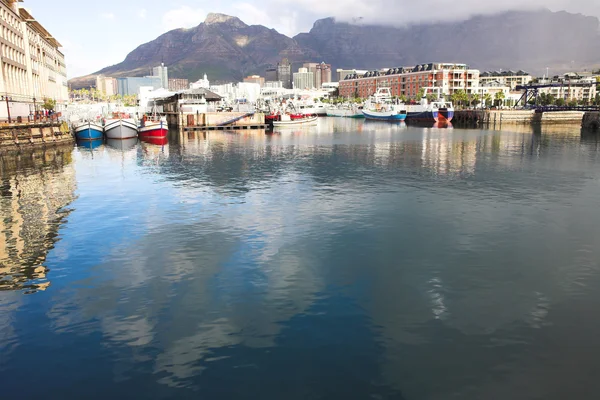 Kapstaden waterfront hamn med tre båtar återspeglar i vattnet och stadens silhuett i bakgrunden. — Stockfoto
