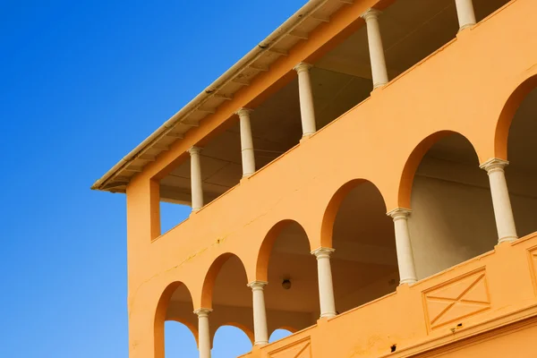 Yellow coloured building with pilars and blue sky — Stock Photo, Image
