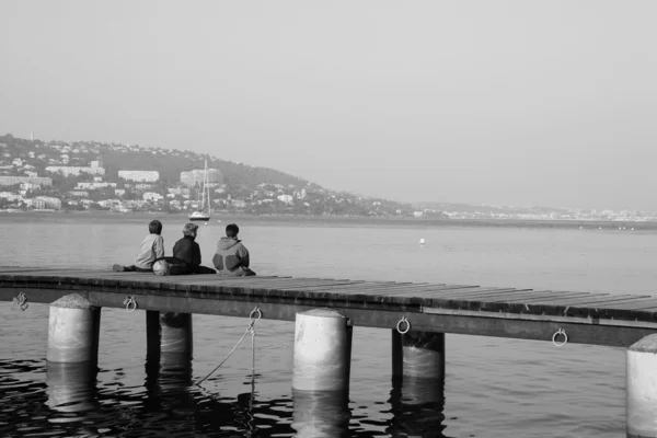 Tres niños pescando en el muelle de Ile Sante-Marguerite Cannes en segundo plano, Francia - Blanco y negro —  Fotos de Stock