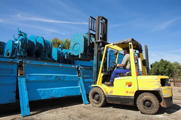 Gele vorkheftruck plaatsen van lading op flatbed truck voor verzending — Stockfoto