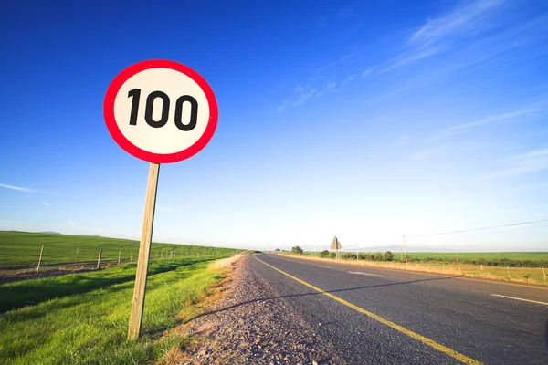 Warning sign or road sign for the maximum speed limit next to an empty road on a sunny summer day. — Stock Photo, Image