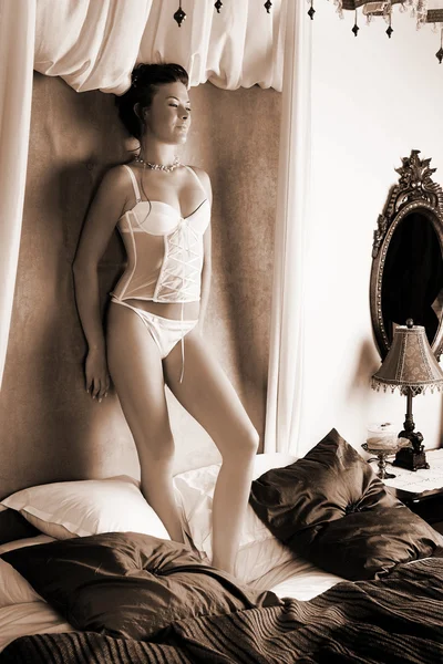 Kvinna i underkläder stående på en säng. — Stockfoto