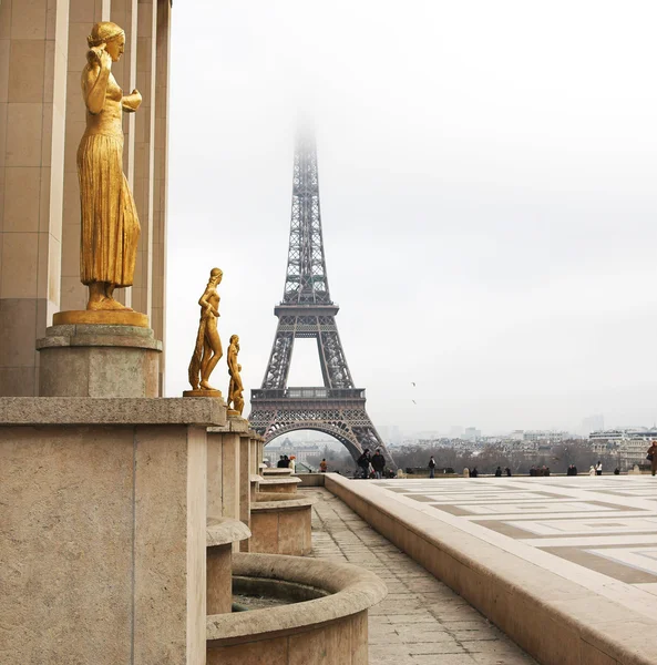 Złoty posąg na pierwszym planie z wieży Eiffla w Paryżu, Francja. — Zdjęcie stockowe