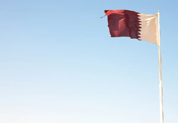 Bandeira nacional do Qatar acenando contra um céu azul do deserto (movimento nas bordas ) — Fotografia de Stock