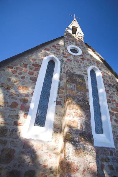 Katolska kyrkan byggnad med ett kors på tornet mot en solig blå himmel — Stockfoto