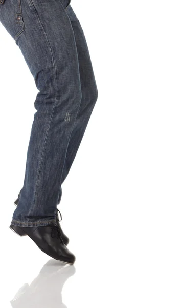 Одноместный танцор чечетки в джинсах, показывающий различные шаги в студии с белым фоном и отражающим полом . — стоковое фото