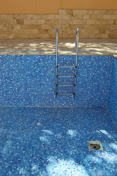 Blauw betegelde lege zwembad op een zonnige dag zonder water — Stockfoto