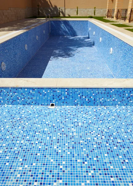 Blauw betegelde lege zwembad op een zonnige dag zonder water — Stockfoto