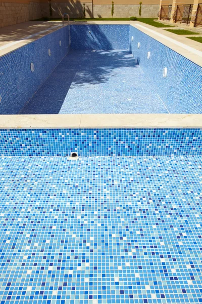 Blau gefliestes leeres Schwimmbad an einem sonnigen Tag ohne Wasser — Stockfoto