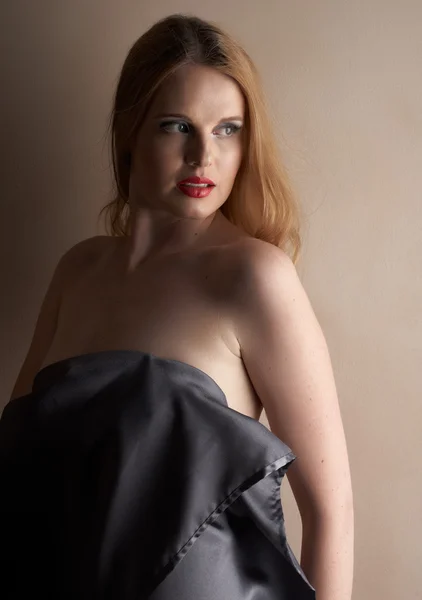 Sexy junge kaukasische erwachsene Frau mit roten Lippen und blonden Haaren steht vor einer neutralen braunen Wand — Stockfoto