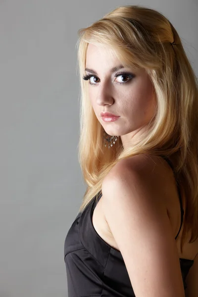 Jeune femme caucasienne adulte aux cheveux blonds et bijoux proéminents sur un fond gris neutre avec lingerie noire et grands yeux marron — Photo
