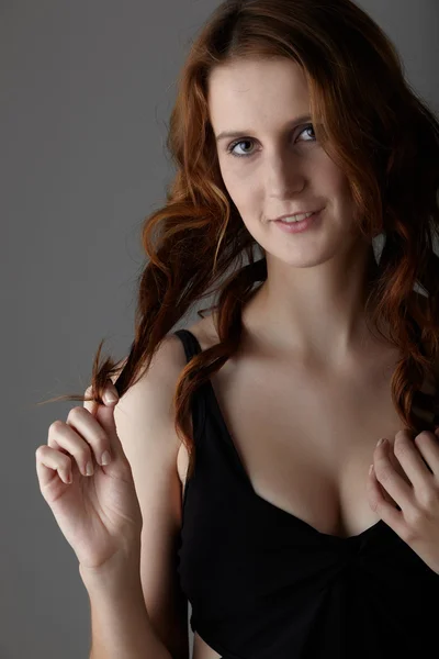 Jovem mulher ruiva adulta caucasiana com olhos verdes e pele muito clara em um pequeno vestido preto em um fundo cinza neutro — Fotografia de Stock