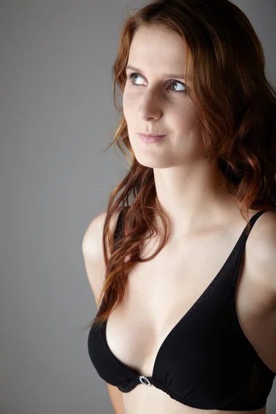 Young caucasian adult redhead woman with green eyes and very fair skin in a little black dress on a neutral grey background — Stock Photo, Image