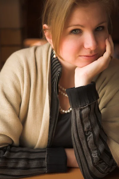 Blonde kaukasische erwachsene Frau sitzt im beginnenden Winter neben einem Fenster mit natürlichem Licht. — Stockfoto