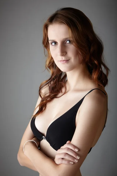 Jonge Kaukasische volwassen redhead vrouw met groene ogen en zeer eerlijke huid in zwarte lingerie op een neutrale grijze achtergrond — Stockfoto