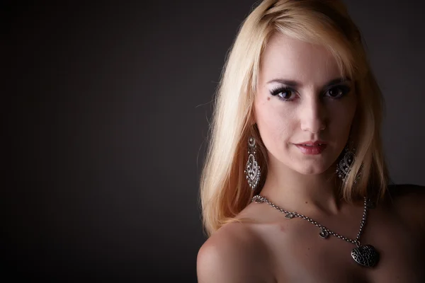 Młodych dorosłych nago kaukaski kobieta z blond włosy i wybitnych Biżuteria na neutralnym szarym tle. domniemane nagość — Zdjęcie stockowe