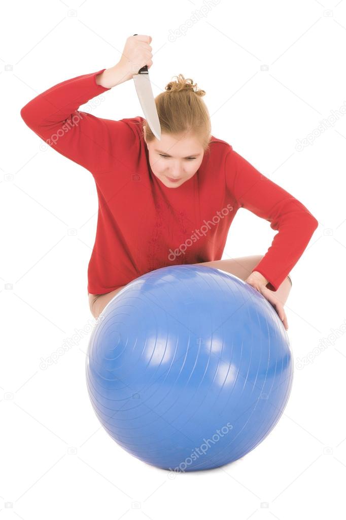 Frustrated blonde middle aged woman with a large carving knife about to kill a yoga ball
