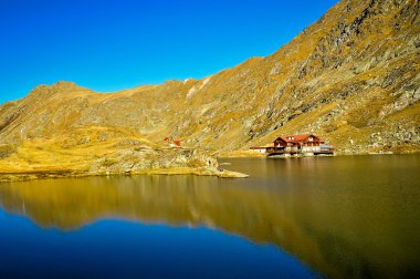 buzul Gölü çok açık dağ su, balea lac, Romanya ile kahverengi ahşap ev