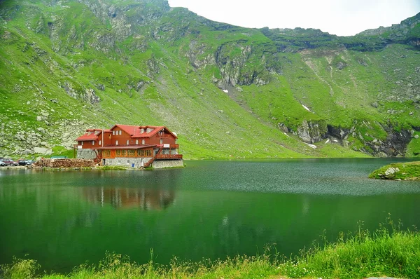 Brown wooden house on glacier lake with very clear mountain water, Balea Lac, Romania — Stock Photo, Image