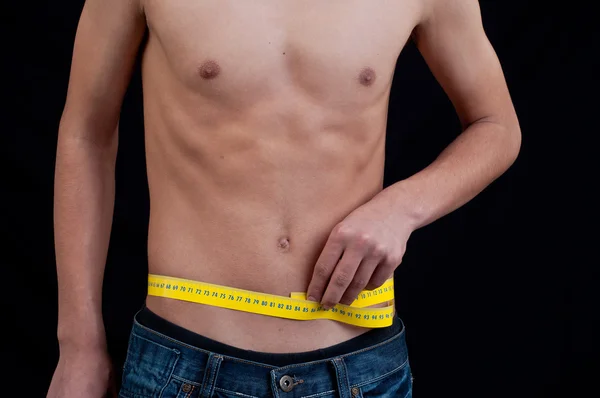 A man measuring his waist isolated on black — Stock Photo, Image