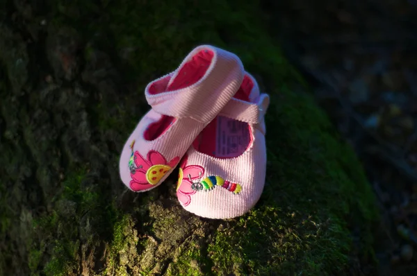 Zapatos de bebé de color rosa en un entorno natural verde — Foto de Stock