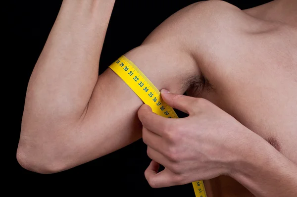 Close up of young man measuring his arm with centimeter — Stock Photo, Image