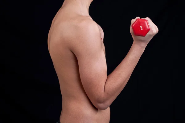 Ajuste jovem exercitando com haltere no fundo preto — Fotografia de Stock