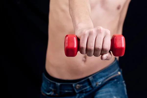 Young man trains muscles of the hands, isolated on black — Stock Photo, Image