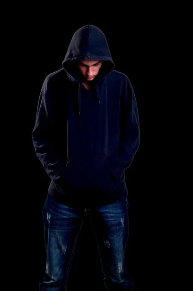 Tiener met hoodie neer te kijken op zwarte achtergrond — Stockfoto