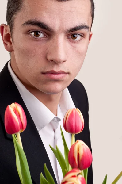 Junger Mann bietet Tulpenblumen an — Stockfoto