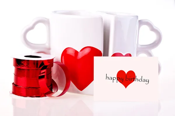 Happy birthday. Coffee mugs in shape of hear and ribbon — Stock Photo, Image