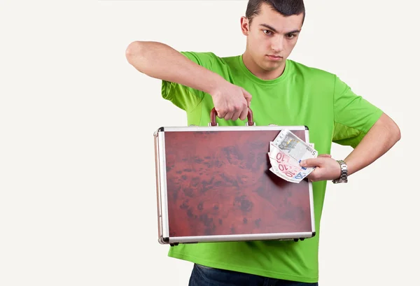 Young man holding and showing a briefcase and money — Stock Photo, Image