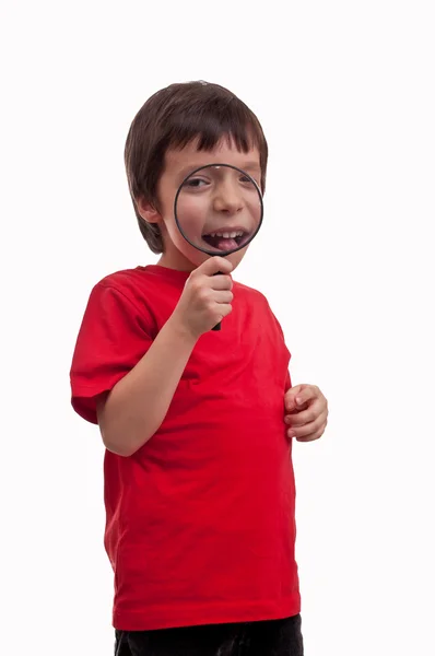 Kleiner Junge spielt mit Lupe auf weißem Hintergrund — Stockfoto