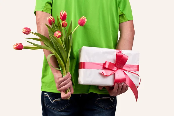 Homem escondendo flores e caixa de presente nas costas — Fotografia de Stock