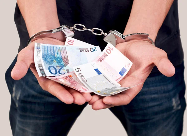 Крупним планом чоловік в наручниках тримає гроші — стокове фото
