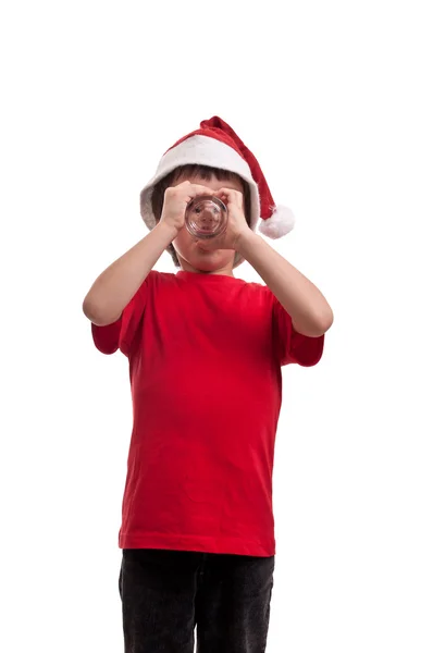 Rolig liten pojke i hatt av jultomten dricksvatten för ett glas på vit bakgrund — Stockfoto