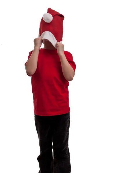 Lyckligt barn drar över ansiktet hans santa hatt att dölja — Stockfoto