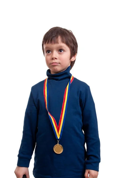Allvarligt liten pojke med guldmedalj vid halsen isolerad på vit — Stockfoto