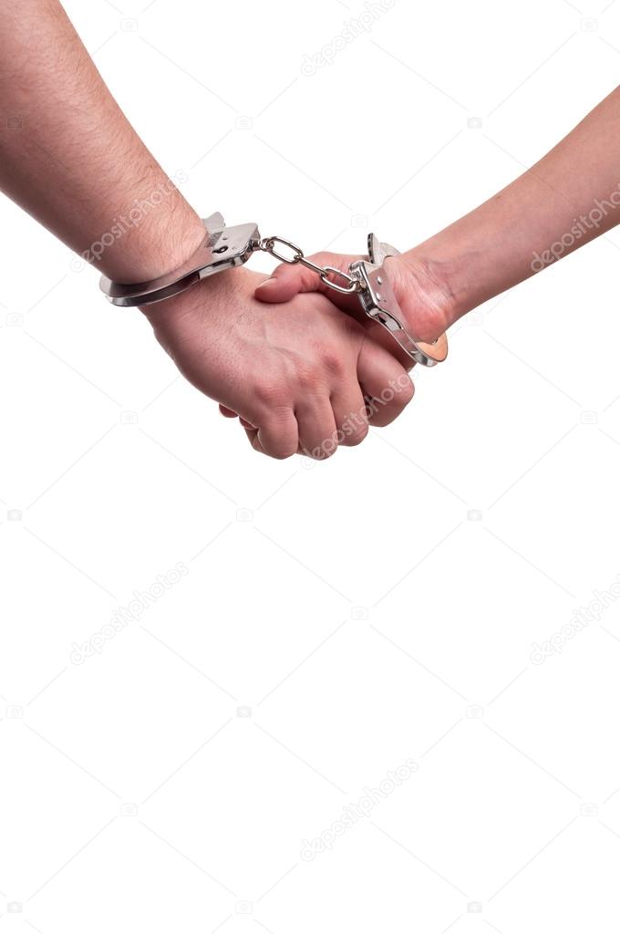 Man and woman holding hands in handcuffs - relationship concept
