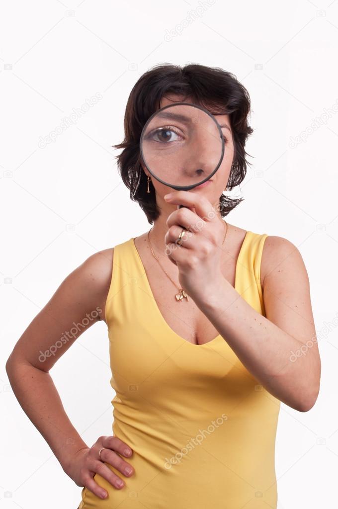 Young woman with magnifying glass at her eye